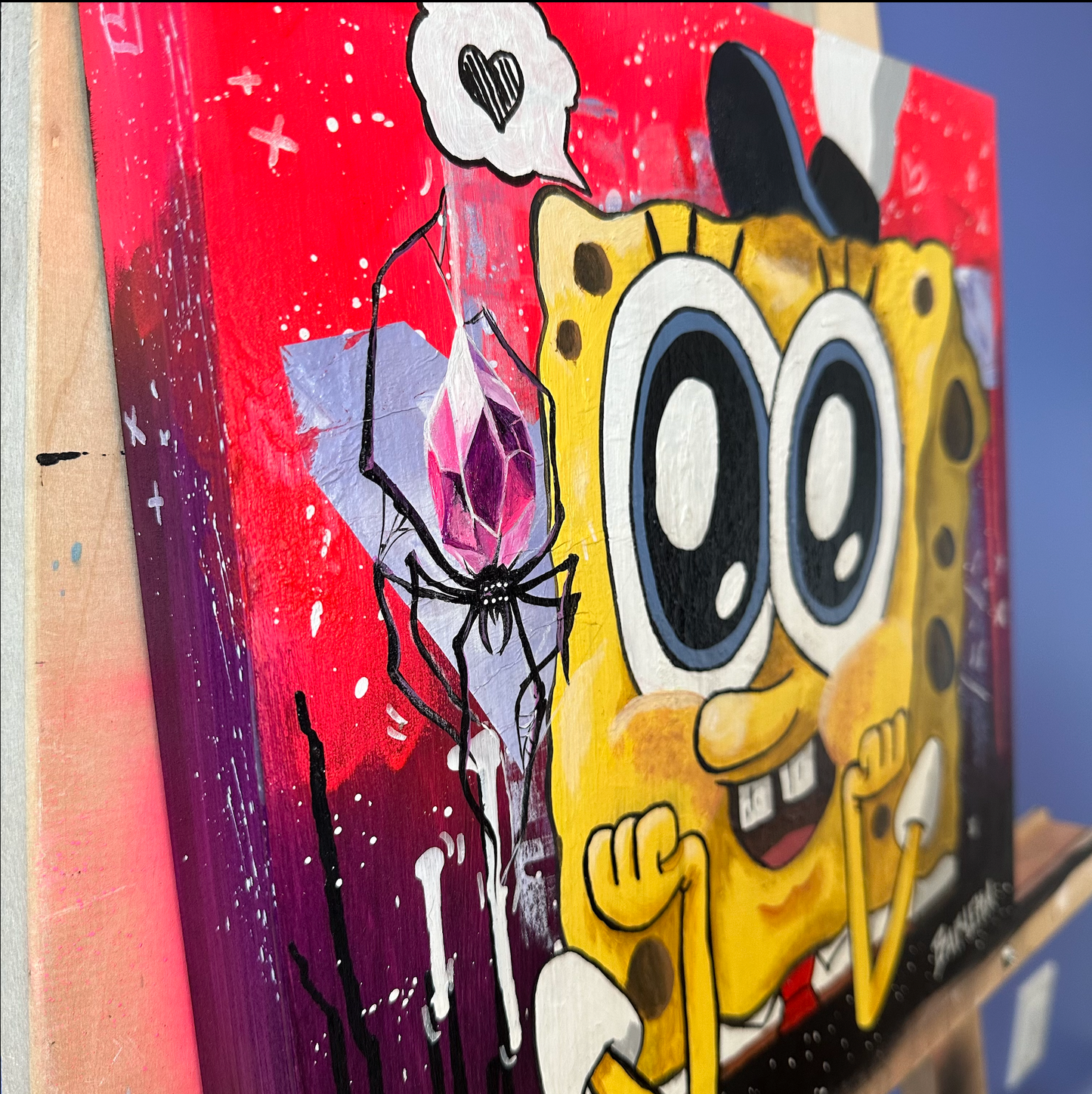 side view of an acrylic painting on wood canvas made by the artist Catherine Barletta. showing a weird love between SpongeBob and a shinny crystal spider